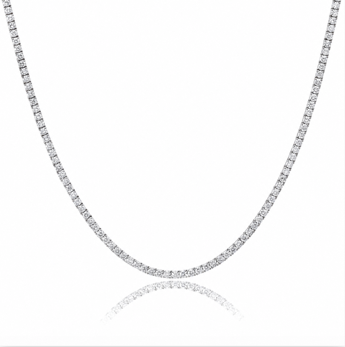A silver tennis chain necklace paved with small clear stones, shown on a white background with a soft reflection below.
