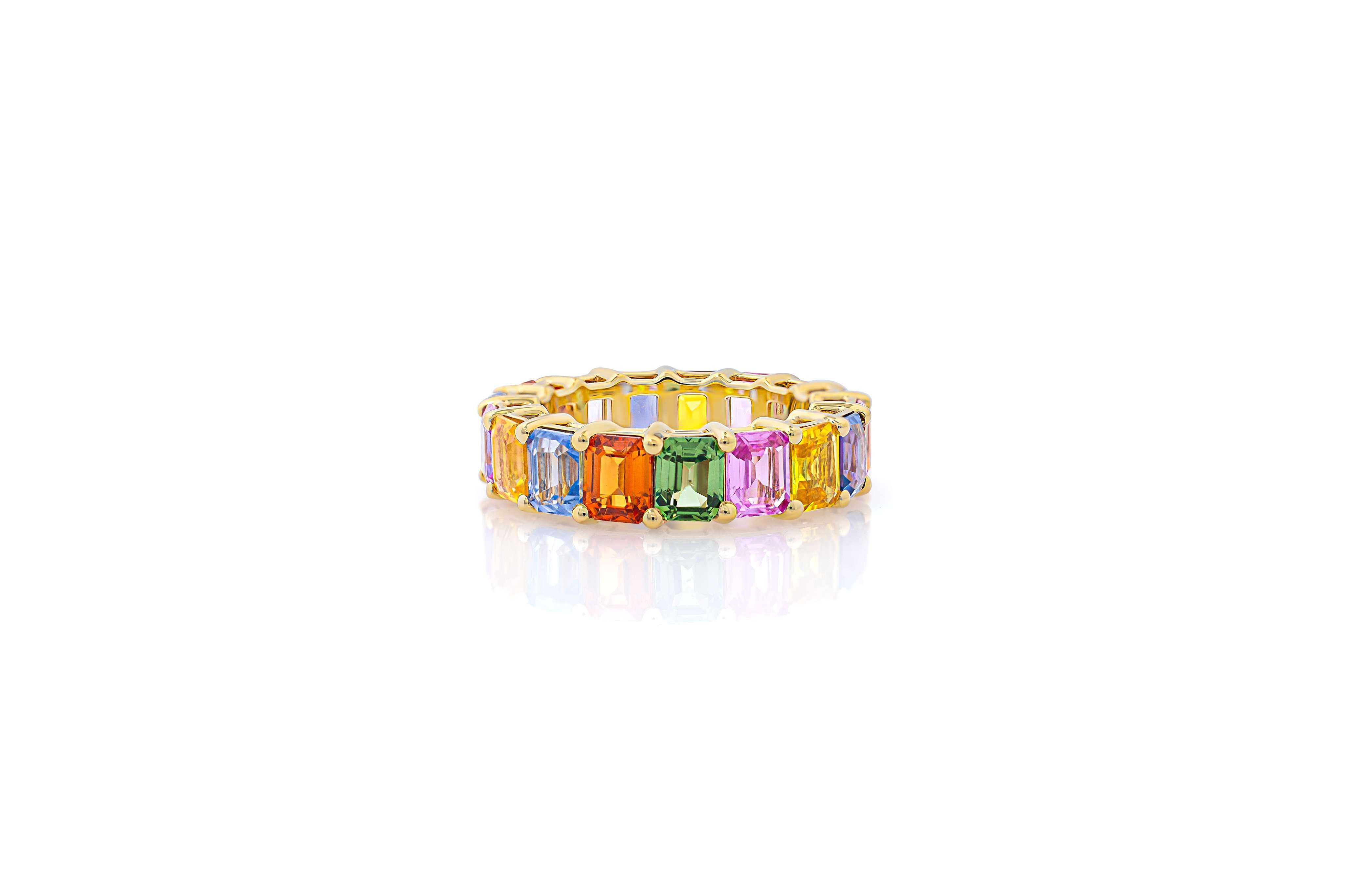 A multicolor emerald cut eternity band ring in yellow gold.