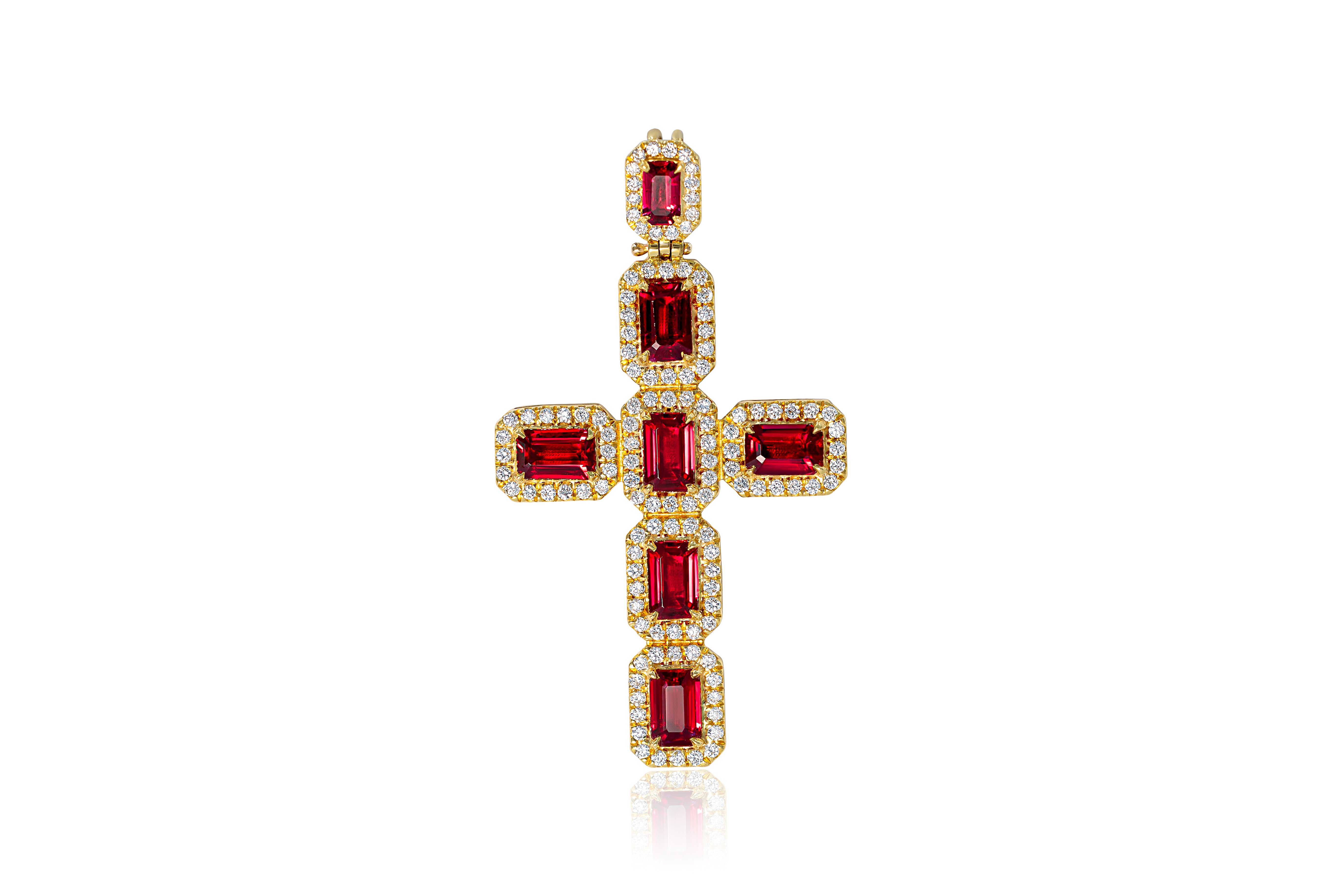 Gold cross pendant with red gemstones on a white background