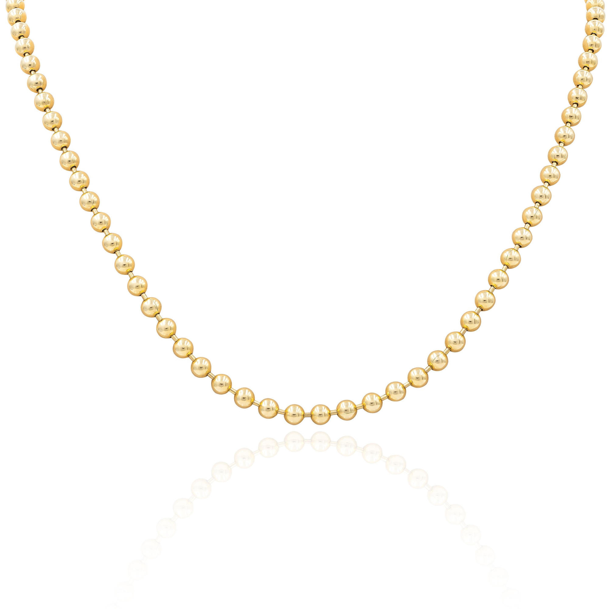 A small yellow gold ball chain necklace laid out on a plain surface.