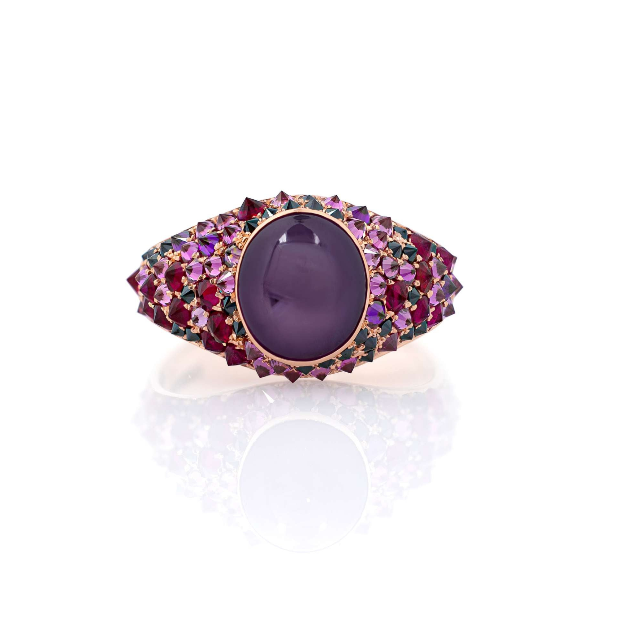 A spiked ring featuring a large purple star sapphire center stone, surrounded by smaller purple and black diamonds set in a gold metal band.