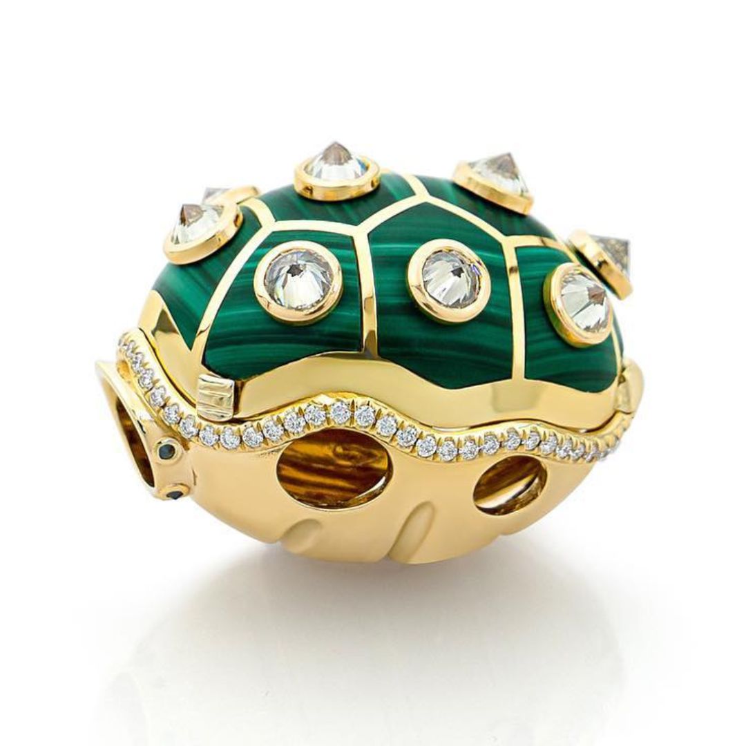 A gold bowser shell pendant with a green enamel design and embedded white diamonds along the edges and sides.